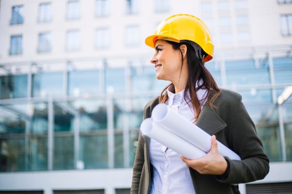 A female engineer in a hard hat holding plans for Professional Engineers Day